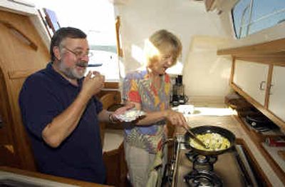 
Dick Sayre sneaks a bite of cream cheese while his wife Karen Sayre prepares a brunch dish of eggs scrambled with cream cheese aboard their sailboat on Lake Coeur d'Alene. 
 (Photos by Jesse Tinsley/ / The Spokesman-Review)