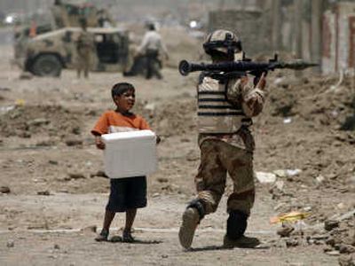 
A young boy offers cold water to an Iraqi army soldier carrying a rocket-propelled grenade launcher during the beginning of combat operations in Amarah, Iraq, on Thursday. Associated Press
 (Associated Press / The Spokesman-Review)