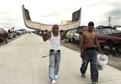 Associated Press photos Roman Knight, left, and his brother Curtis Pearson, both of Detroit, carry a front bumper for Knight's car at Parts Galore in Detroit. Soaring scrap metal prices are  making do-it-yourself salvage yards far more profitable than they once were.
 (Associated Press photos / The Spokesman-Review)