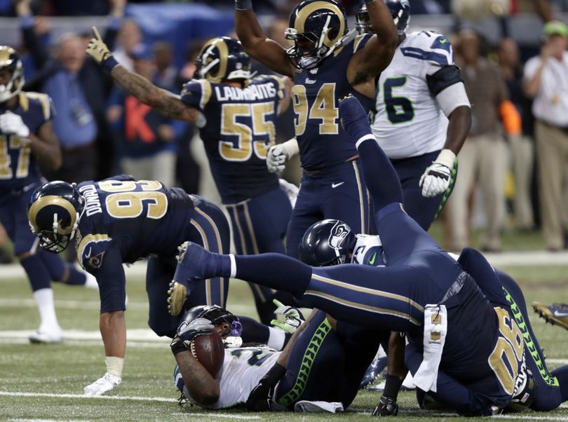 Seahawks running back Marshawn Lynch, bottom, lands on his back after being stopped on fourth down by the Rams to end Sunday’s game. (Associated Press)