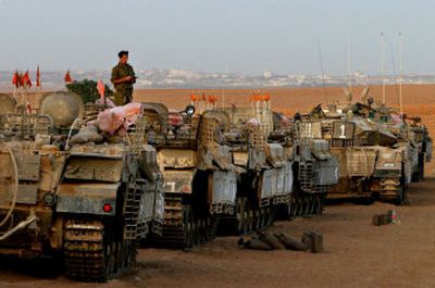 
An Israeli soldier stands on top of an armored carrier as he takes part in morning prayers at a staging area near Kibbutz Mafalsim, just outside the northern Gaza Strip on Tuesday. 
 (Associated Press / The Spokesman-Review)