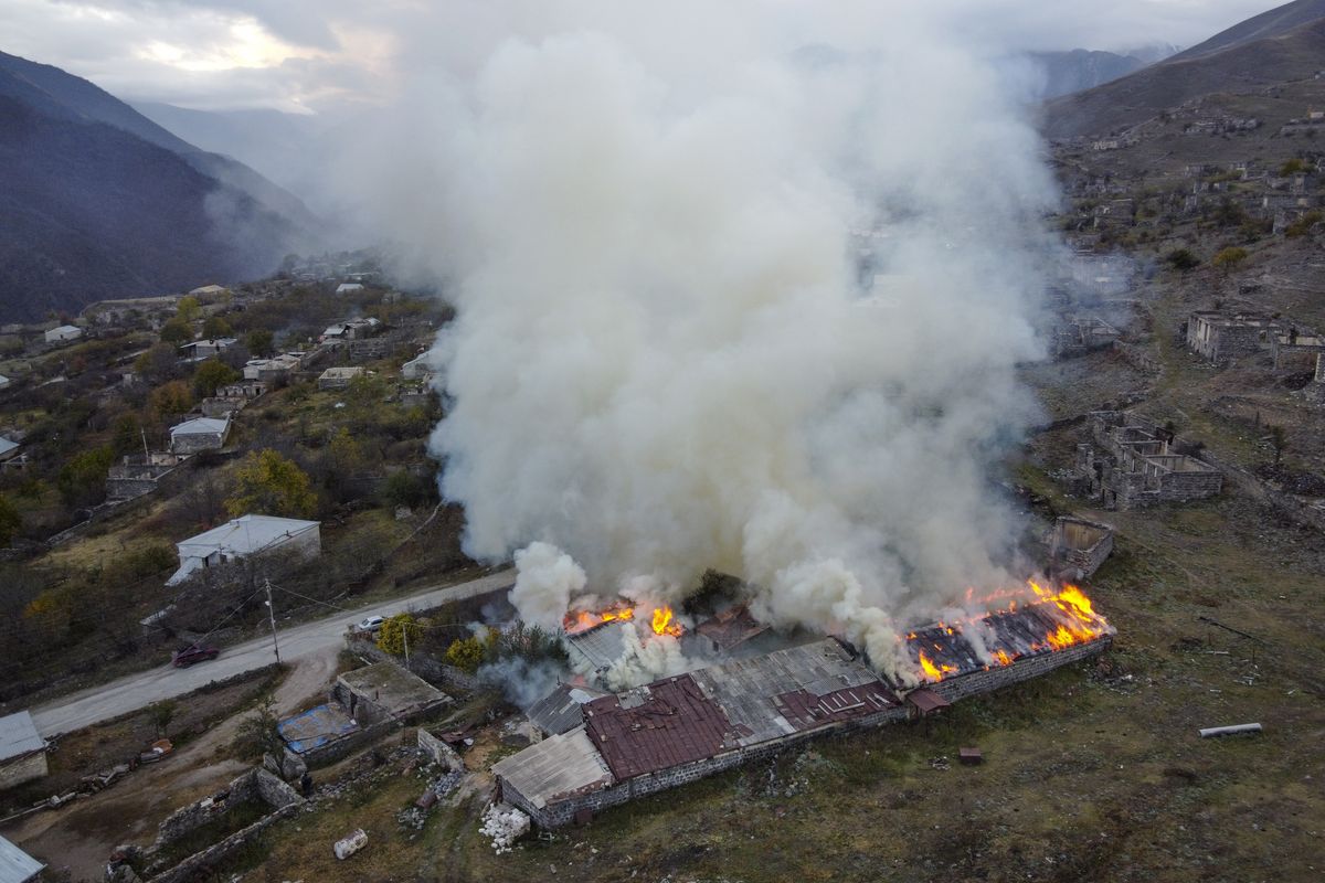 Smoke rises from a burning house in an area once occupied by Armenian forces but soon to be turned over to Azerbaijan, in Karvachar, the separatist region of Nagorno-Karabakh, on Friday, Nov. 13, 2020. Under an agreement ending weeks of intense fighting over the Nagorno-Karabakh region, some Armenian-held territories adjacent to the region are passing to Azerbaijan.  (Dmitry Lovetsky)