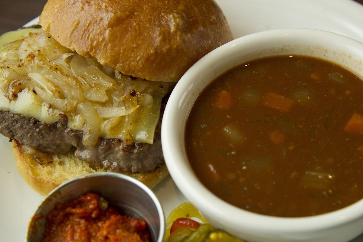 The Central Burger features comte cheese, caramelized onions, house-made pickles and romesco with a side of lentil soup.