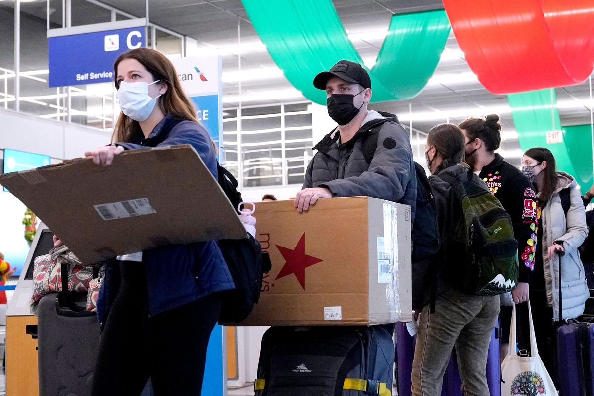 FILE - Travelers line up wearing protective masks indoors at O