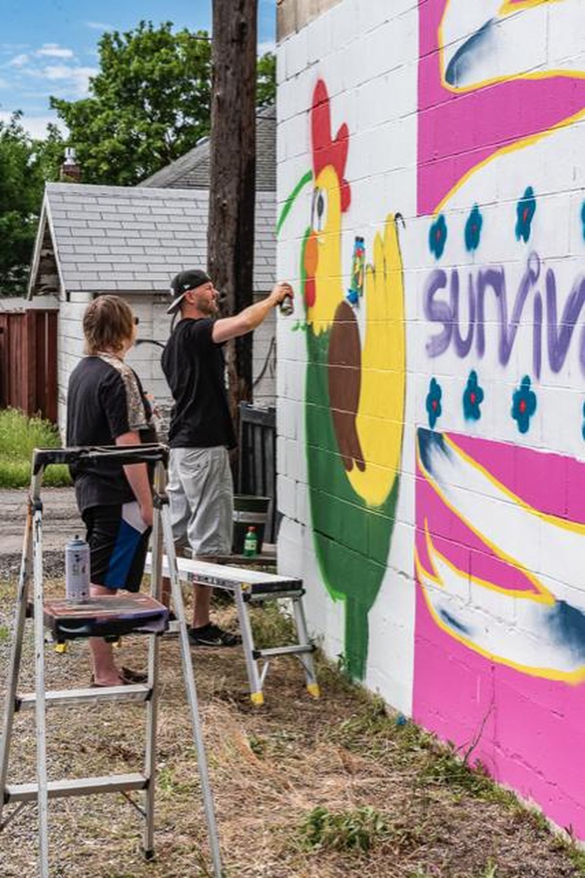 Artist Jeramee Sauls helps student Alex Parlange, left, on his chicken mural that went up Saturday, May 19, 2018, in the Garland Avenue mural alley between Post and Monroe streets. Parlange, a student at Excelsior Youth Center, raises chickens at home. (M’Liss Bush / Courtesy)