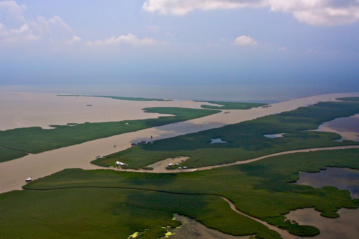 Though the exploded BP oil well has capped, not all the oil has been removed from the Gulf. As this photo shows, oil is still present at the end of South Pass, Louisiana, where the muddy water of the Missississppi meets the Gulf waters.  There is now talk of Port Eads being used as a military missile test site:  (Matthew White / Special to Down to Earth NW)