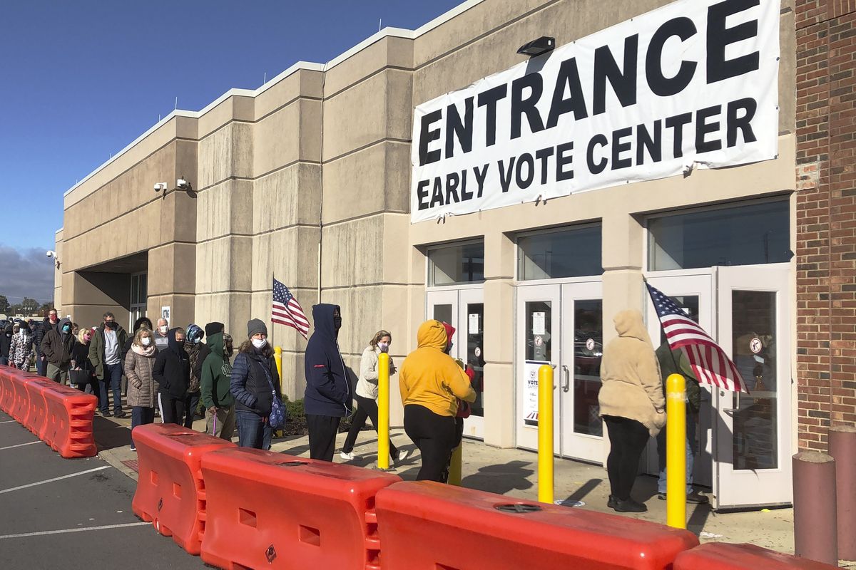 FILE - In this Friday, Oct. 30, 2020 file photo, people bundled against the cold stand in a slowly moving line to cast early votes at the Franklin County Board of Elections in Columbus, Ohio. Early voting ends in Ohio on Monday, Nov. 2. A surge in coronavirus cases across the country, including in key presidential battleground states, is creating mounting health and logistical concerns for voters, poll workers and political parties ahead of Election Day.  (Andrew Welsh Huggins)