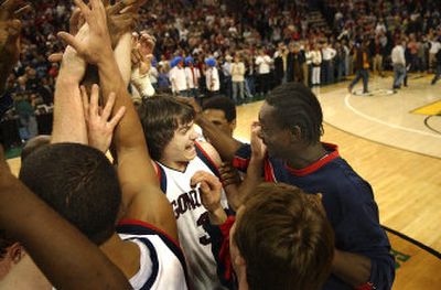 Gonzaga forward Adam Morrison, center, is mobbed by his teammates Saturday after banking in a 3-pointer with 2.5 seconds left to defeat Oklahoma State 64-62 in the Battle in Seattle. 
 (Brian Plonka / The Spokesman-Review)