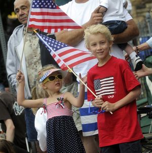 Karsyn Bowlin, 4, and brother Spencer, 7, wave flags  as the parade passes. 
