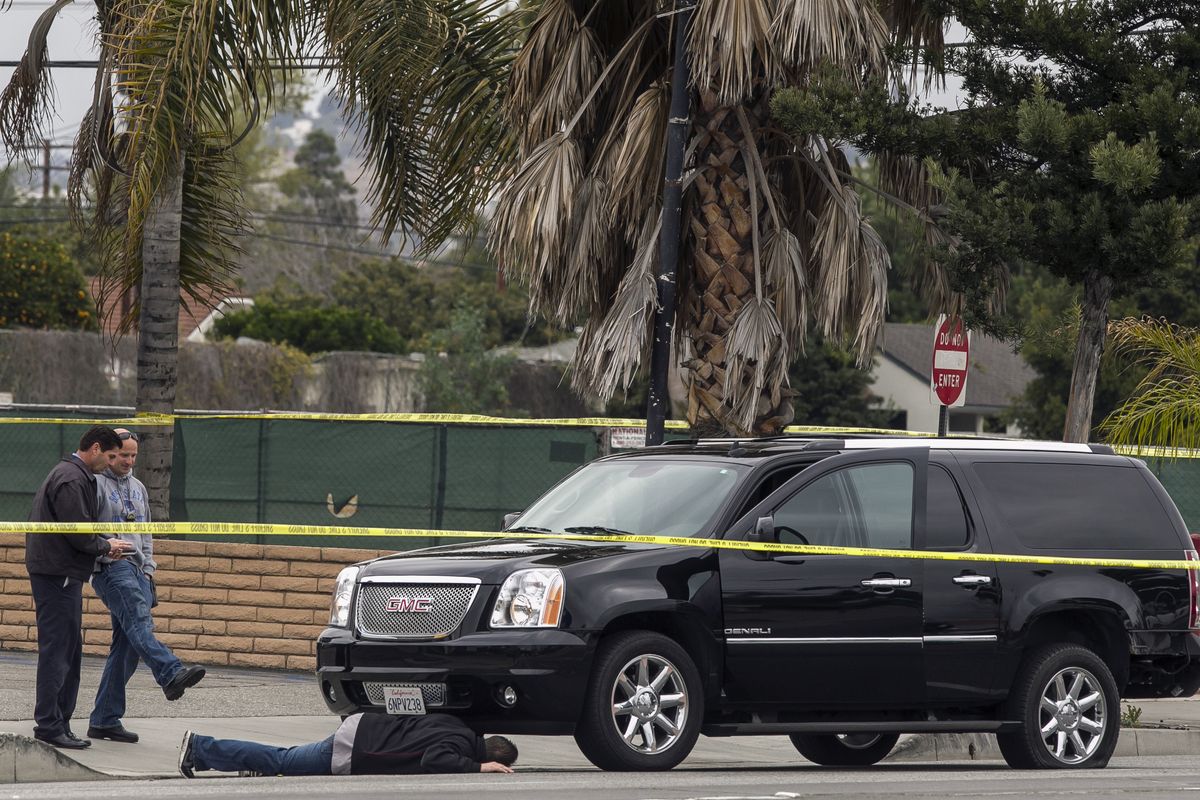 A police investigator looks under a disabled SUV in Tustin, Calif., Tuesday. (Associated Press)