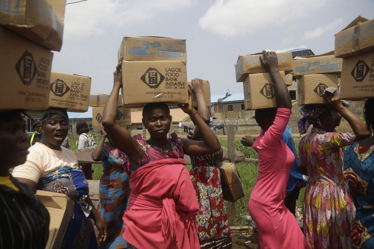 Residents of Oworonshoki Slum carry their food parcels distributed by the Lagos Food Bank Initiative, a non-profit nutrition focused initiative committed to fighting hunger and solving problems of Malnutrition for poor communities , in Lagos, Nigeria, Saturday, July 10, 2021.  (Sunday Alamba)