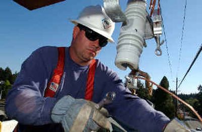 
Portland General Electric lineman Shane Huston works on the installation of power lines on new poles in Beaverton, Ore. PGE is owned by Enron. 
 (Associated Press / The Spokesman-Review)