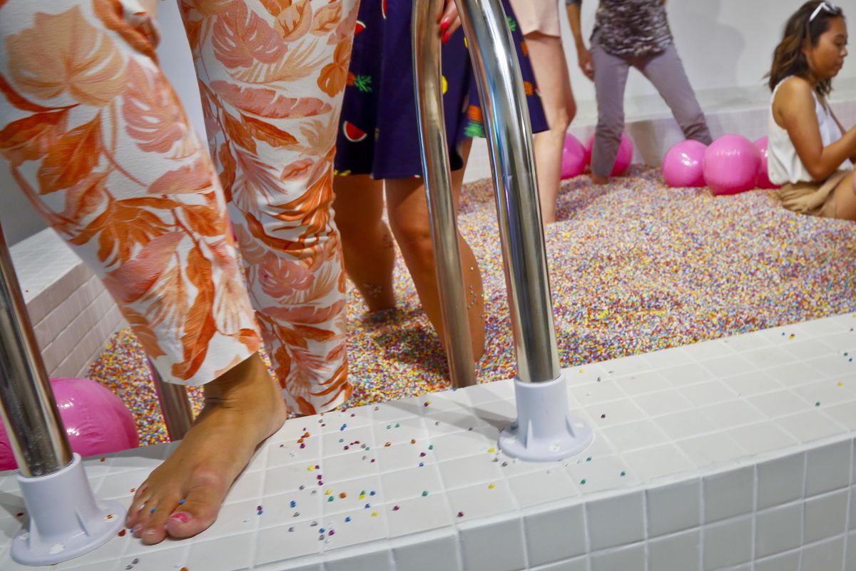 Visitors walk into a large pool filled with faux confetti-colored sprinkles, the biggest attraction of ice cream-themed works of art previewed at the Museum of Ice Cream, Thursday July 28, 2016, in New York. (Bebeto Matthews / Associated Press)