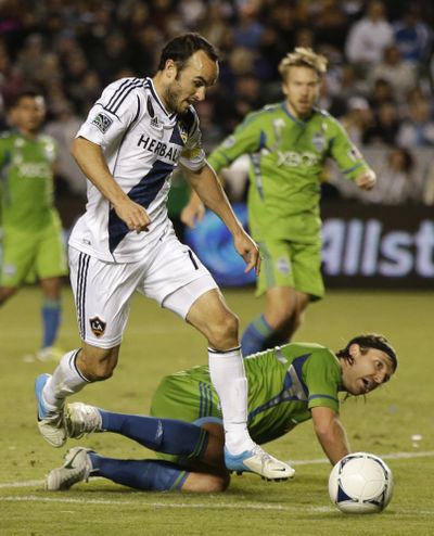 Galaxy’s Landon Donovan slips the ball past Sounders’ Steve Zakuani to set up a goal. (Associated Press)