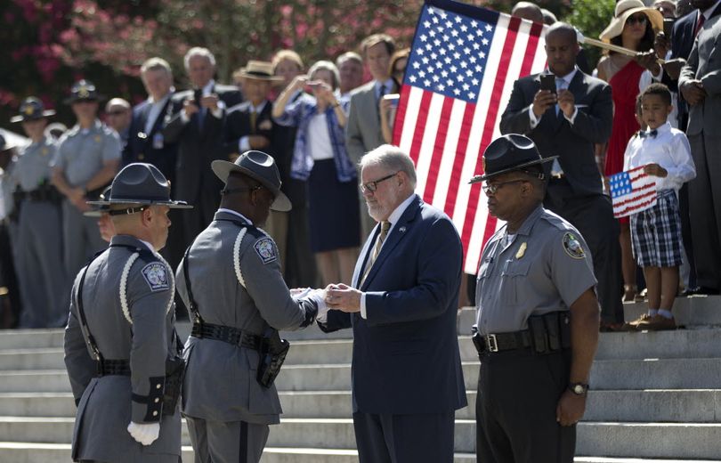 An honor guard member from the South Carolina Highway Patrol hands the Confederate battle flag that flew in front of the Statehouse to the curator of the Confederate Relic Room and Military Museum after it was taken down Friday, July 10, 2015, in Columbia, S.C.  (John Bazemore / Associated Press)