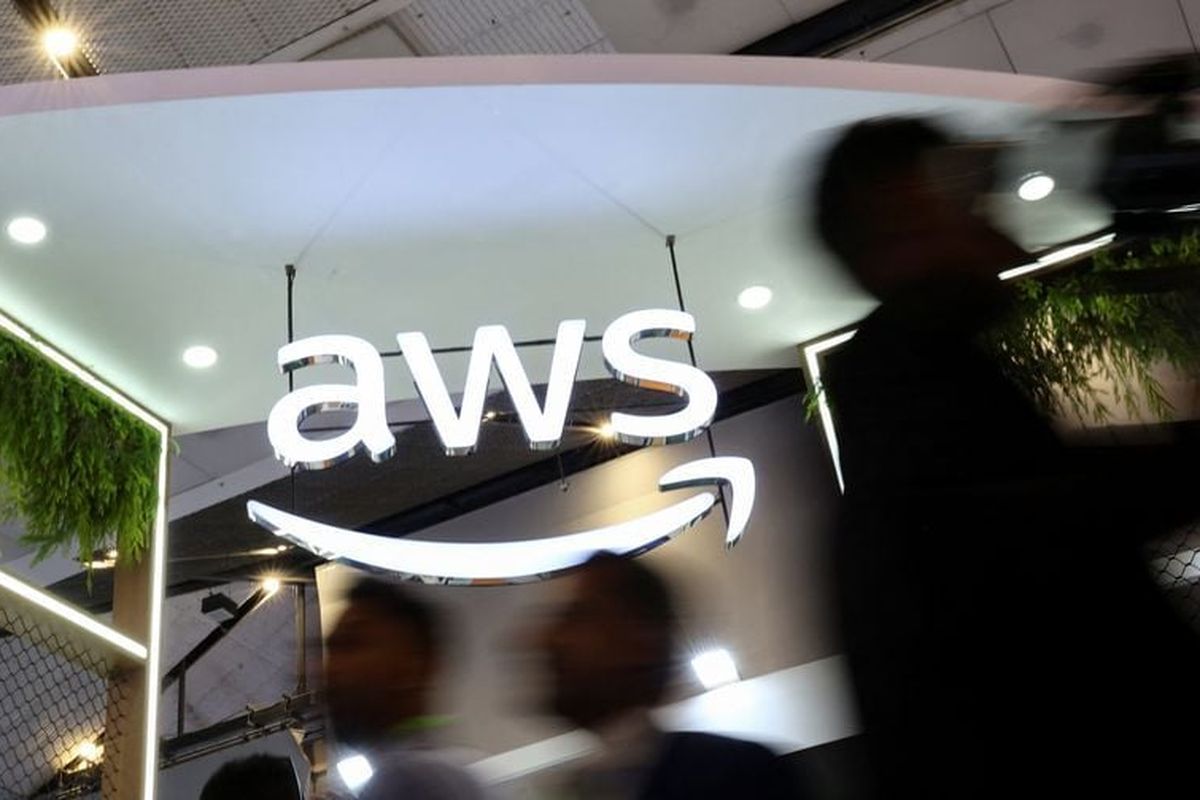 People walk past the logo of Amazon Web Services (AWS) at its exhibitor stall at the India Mobile Congress 2025 at Yashobhoomi, a convention and expo center in New Delhi, India, Oct. 8.   (Reuters )