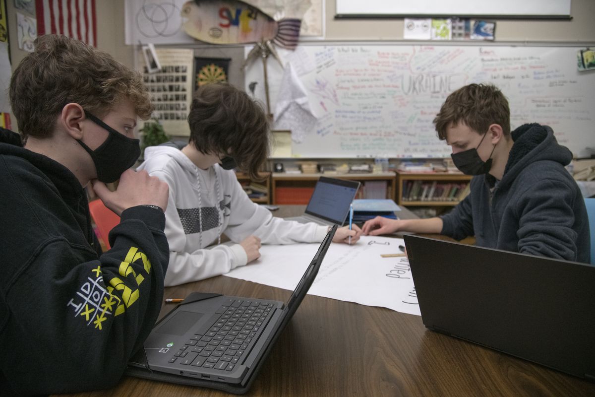 Kaelan Conroy, 15, left, Rose Spessard, 16, and Peter Erickson, 16, work on a poster about World War I on Thursday in their combination English/World History class in front of a whiteboard filled with mentions of news, rumors and propaganda coming out of the war in Ukraine in a classroom at Spokane Valley Tech high school.  (Jesse Tinsley/THE SPOKESMAN-REVIEW)