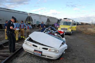 
Idaho State Police Trooper Chris Yount investigates the scene of a car-train crash near Hayden Avenue and Greensferry on Tuesday. The driver, the only person in the vehicle, survived. 
 (Jesse Tinsley / The Spokesman-Review)
