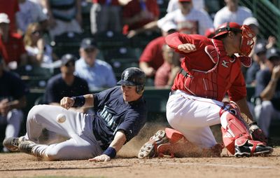 Rob Johnson, left, scoring in a spring training game against the L.A. Angels, has been a valuable addition to the Mariners’ lineup. (Associated Press / The Spokesman-Review)