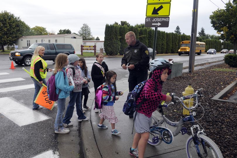 Sheriff’s Deputy Craig Chamberlin hands out “Stickman Knows” tattoos, reflective stickers and wristbands at Otis Orchards Elementary School as a part of International Walk to School Day on Wednesday. The school has improved the safety of children walking and biking to school and being picked up by parents after school. (J. Bart Rayniak)