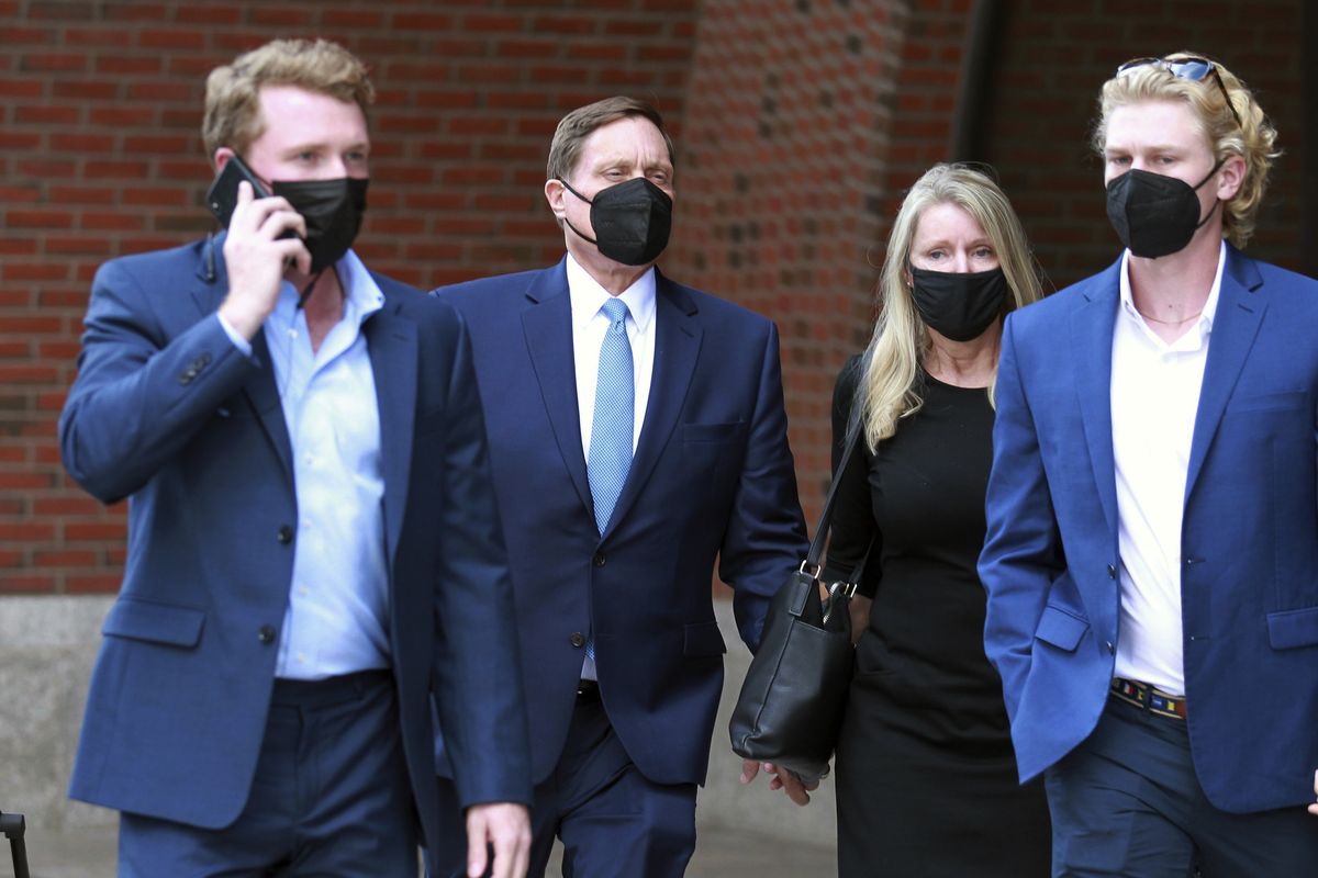 John Wilson, second left, holds his wife’s hand, second right, as he leaves the John Joseph Moakley Federal Courthouse after the first day of his trial in the college admissions scandal Monday in Boston.  (Stew Milne)