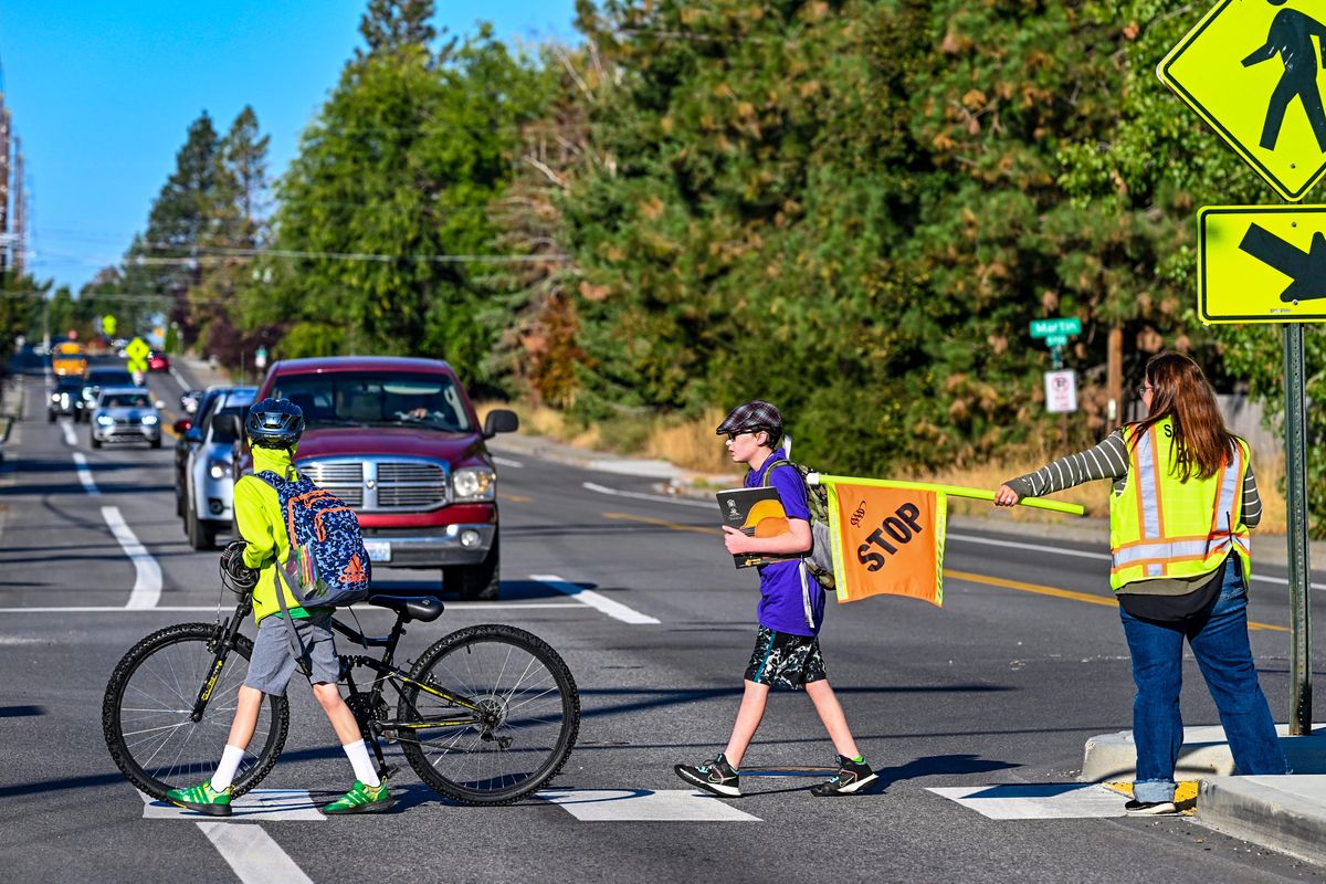 Sixth grade student Cael Fitzgerald, center, crosses 57th Avenue at Crestline Street with help from Peperzak Middle School Assistant Principal Cori Fletcher, right, on Wednesday morning in Spokane.  (DAN PELLE/THE SPOKESMAN-REVIEW)