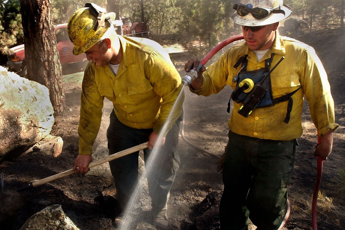 Cody Traber, right, and Eddie Lewis uncover and soak remaining hot spots at a fire on Beacon Hill in this September 2002 photo. Traber died Thursday while working at the scene of an emergency, officials said.  (ROBERT J SHAER)