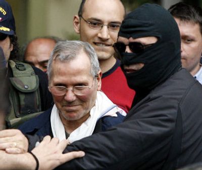 
Mafia boss Bernardo Provenzano is escorted by a black-hooded police officer as he enters a police building Tuesday in Palermo. Italy's reputed No. 1 Mafia boss had been on the run since 1963. 
 (Associated Press / The Spokesman-Review)