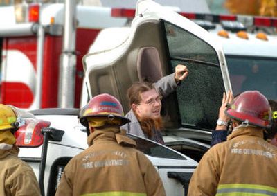 
Christopher A. Mangum, of Spokane, crawls out of the 2001 Kia Sportage that flipped in a collision  with a Spokane Valley police car  Monday on Mission Avenue. 
 (Joe Barrentine / The Spokesman-Review)