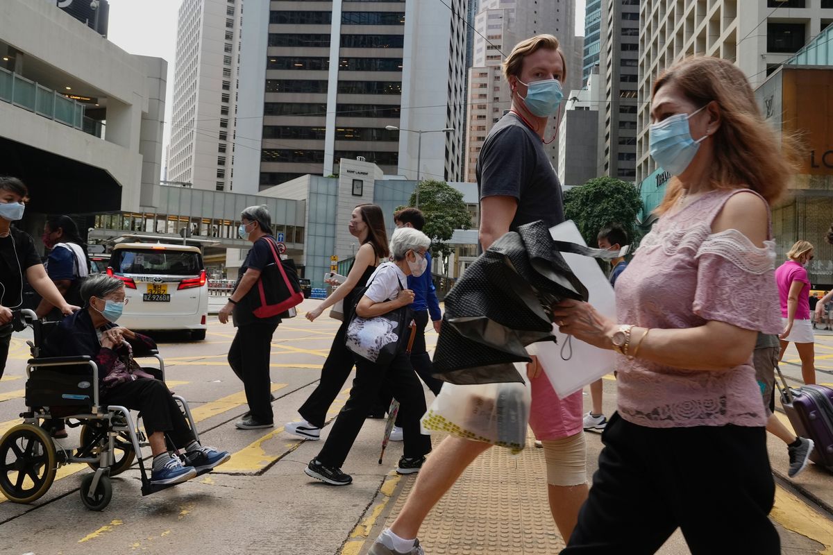 People wearing face masks to prevent the spread of coronavirus walk on a downtown street in Hong Kong, Tuesday, Aug. 17, 2021. Hong Kong will tighten entry restrictions for travelers arriving from the United States and 14 other countries from Friday, increasing the quarantine period to 21 days. (Vincent Yu)