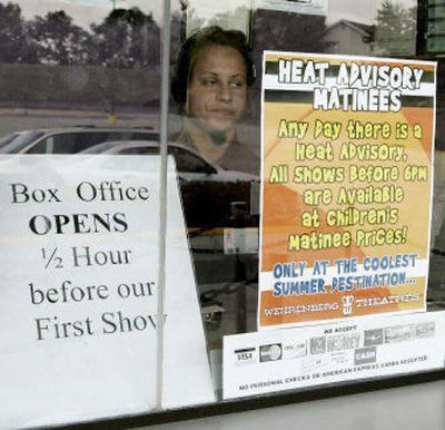 
Katie Schwarztarauber sits in the box office at Kenwick theater, a Wehrenberg Theater, in front of a sign indicating a special price offer for moviegoers during the St. Louis heat crisis Tuesday. Wehrenberg, based in St. Louis, has seen attendance rise 11 percent during the heat.
 (Associated Press / The Spokesman-Review)
