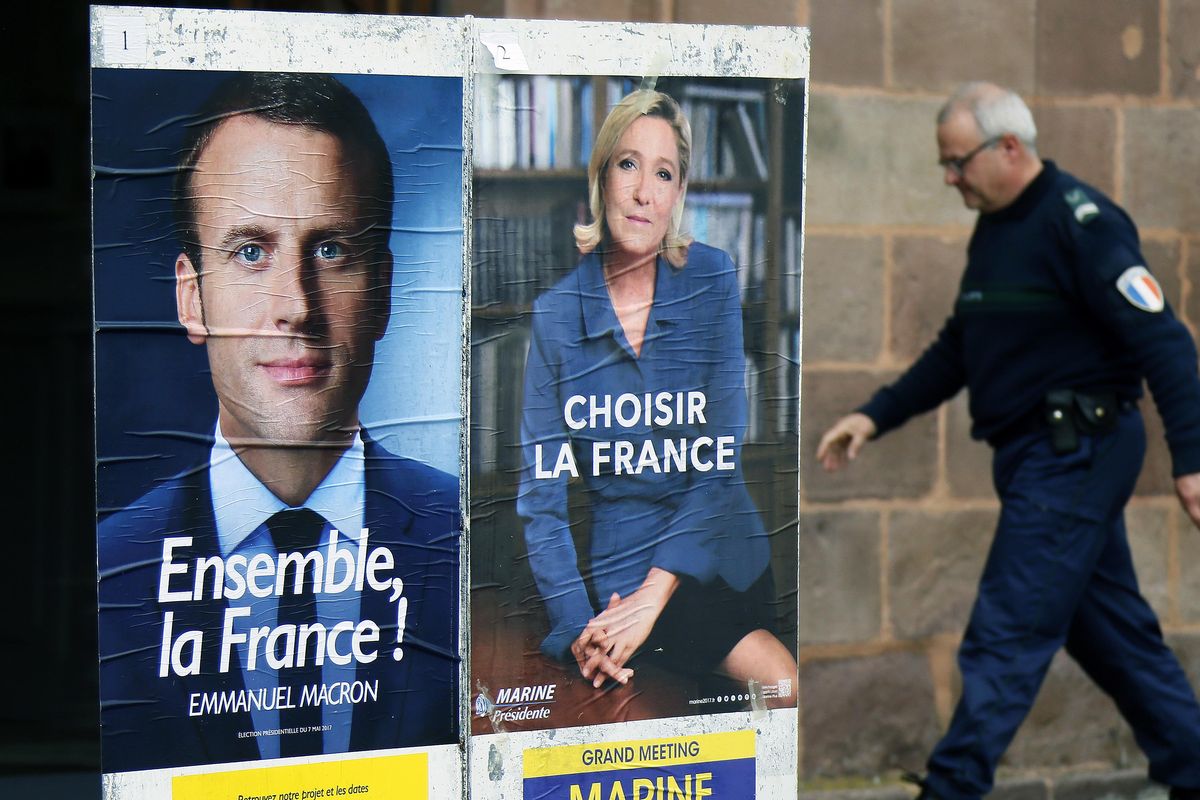 A municipal police officer walks near election campaign posters for French centrist presidential candidate Emmanuel Macron, left, and far-right candidate Marine Le Pen, in Saint Jean Pied de Port, southwestern France, Friday May 5, 2017. The second round of the French presidential election will take place Sunday May 7. (Bob Edme / Associated Press)