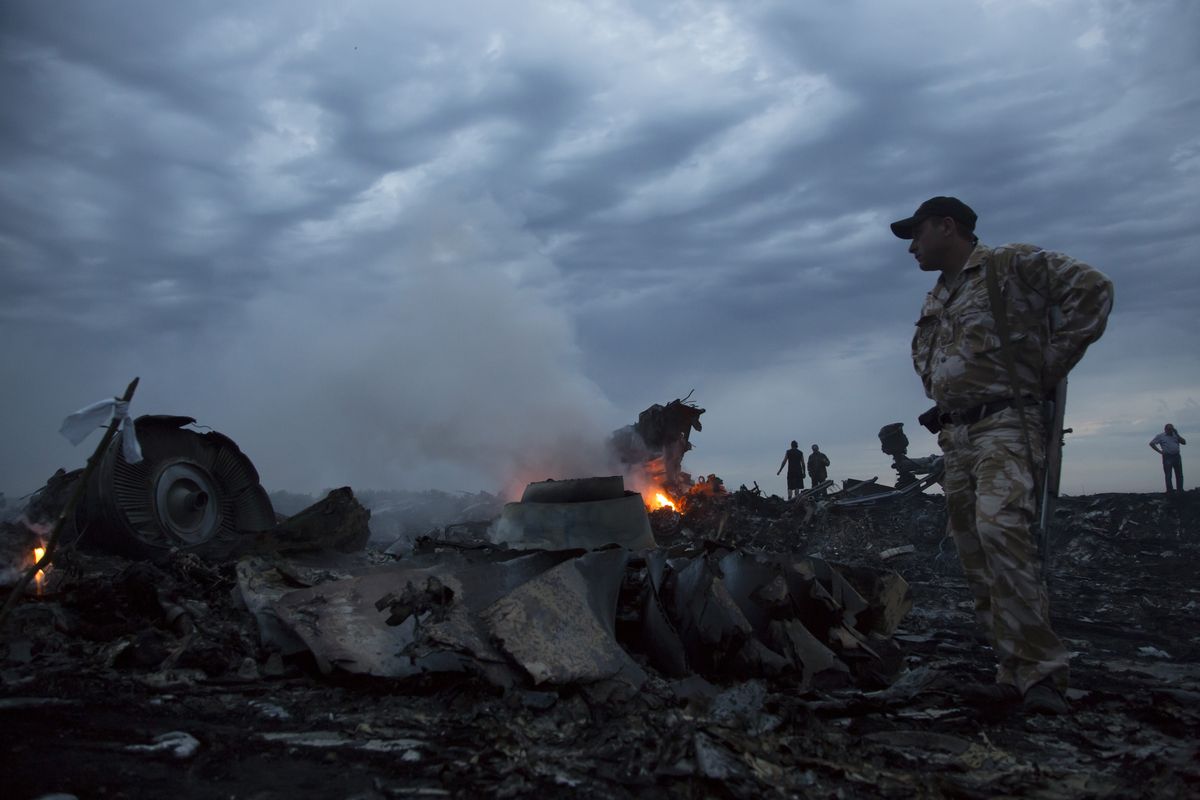 People walk amongst the debris, at the crash site of a passenger plane near the village of Grabovo, Ukraine, Thursday, July 17, 2014.  A Ukrainian official said a passenger plane carrying 295 people was shot down Thursday as it flew over the country and plumes of black smoke rose up near a rebel-held village in eastern Ukraine. Malaysia Airlines tweeted that it lost contact with one of its flights as it was traveling from Amsterdam to Kuala Lumpur over Ukrainian airspace. (Dmitry Lovetsky / Associated Press)