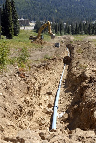 Pipe to transport water via a gravity  system  is put into a trench being dug on Midway Run for use of snowmaking equipment.  (J. Bart Rayniak / The Spokesman-Review)
