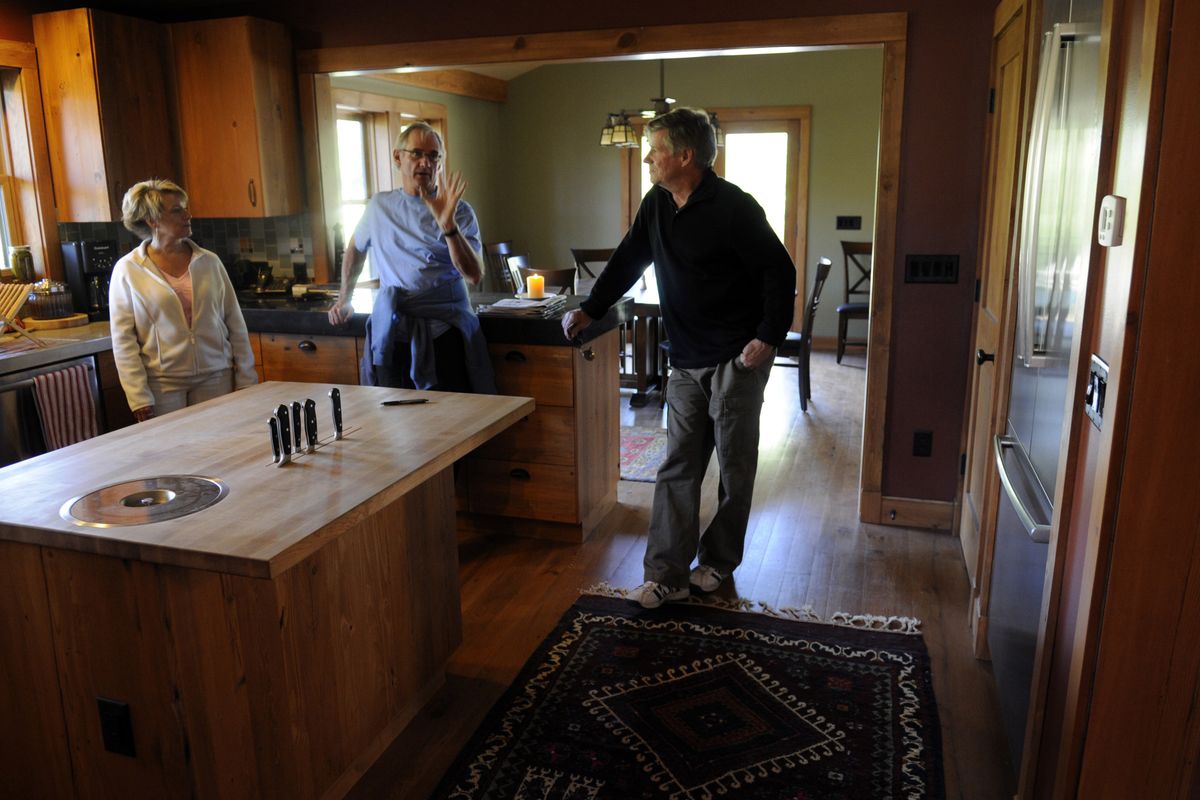 Jim Sheehan, center, shows off his kitchen to Lynnette Vehrs and Denny Dellwo during the Spokane Green + Solar Home and Landscape Tour on Sunday. The room features locally made cabinets and salvaged trim. The kitchen island, made of recycled wood, has a built-in compost bin. (J. BART RAYNIAK / The Spokesman-Review)