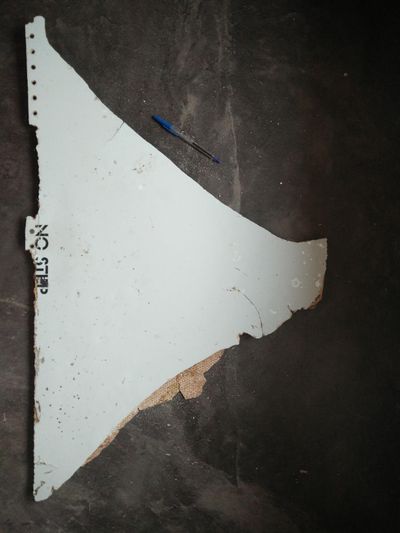 In this Feb. 28, 2016, image provided by Blaine Gibson and the Australian Transport Safety Bureau, a piece of aircraft debris with the words “NO STEP” is photographed after it was found washed up on a beach in Mozambique. Authorities tentatively identified the debris as from the missing Malaysia Airlines Flight 370. (Blaine Gibson / Associated Press)