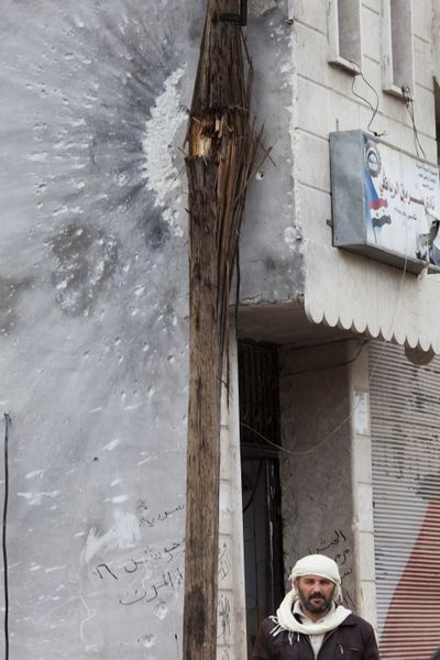 A man walks next to a wall damaged during clashes between the Free Syrian Army and President Bashar Assad’s forces in Sarmin, Syria. (Associated Press)