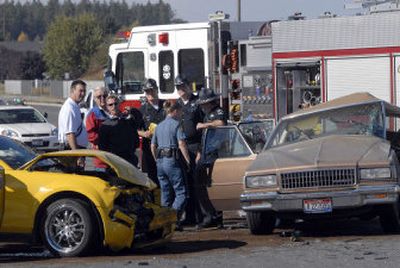 
Firefighters, officers and others stand on Kathleen Avenue by two cars involved in a fatal accident Friday in Coeur d'Alene. Another car rolled after it swerved to avoid the collision. A 14-year-old died in the Chevrolet at right when it was hit by the Mustang at left. Second from left is Kootenai County Coroner Dr. Bob West. 
 (Jesse Tinsley / The Spokesman-Review)