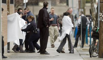 Survivors exit a building near the American Civic Association in downtown Binghamton, N.Y., following a shooting spree by a gunman Friday.  (Associated Press / The Spokesman-Review)