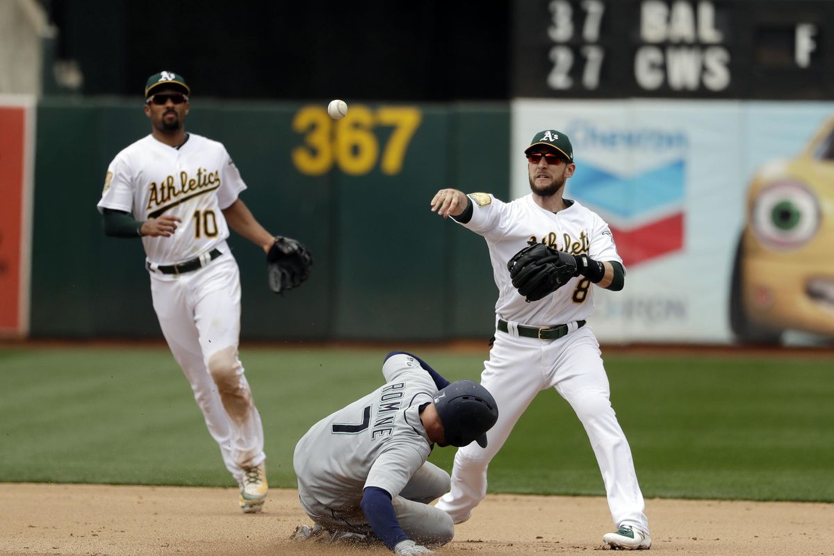Oakland Athletics second baseman Jed Lowrie, right, completes a double play over Seattle Mariners