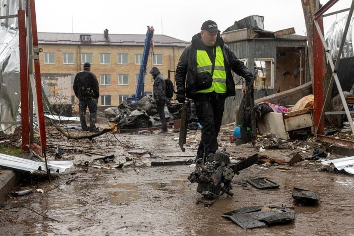An investigator collects debris of a Russian drone at the impact site in a residential neighborhood, amid Russia