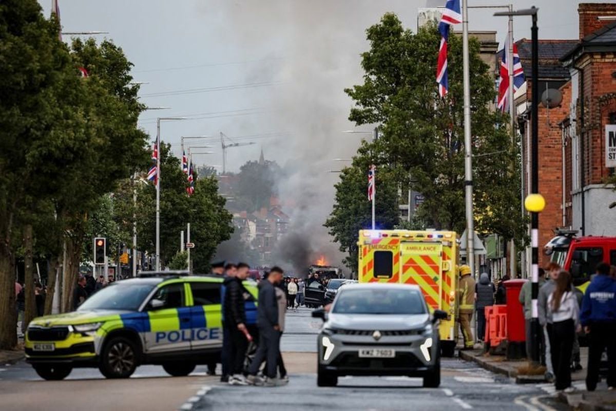 Law enforcement operates as smoke billows from a burning vehicle during a protest after a knife attack on Monday left a man seriously injured and prompted police to declare a critical incident, on Newtownards Road on Tuesday in Belfast, Northern Ireland.   (Reuters )