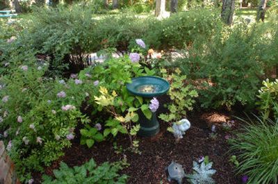 
Keith and Barbara Gray's garden, with several bird baths and items covered with mosaic tiles, will be one of the stops on the Coeur d'Alene Garden Club's annual garden tour on Sunday. Below, tiger lilies can be seen through the profusion of other plants in Bob and Karen Hill's garden in Coeur d'Alene's Bentwood subdivision.
 (JESSE TINSLEY Photos / The Spokesman-Review)