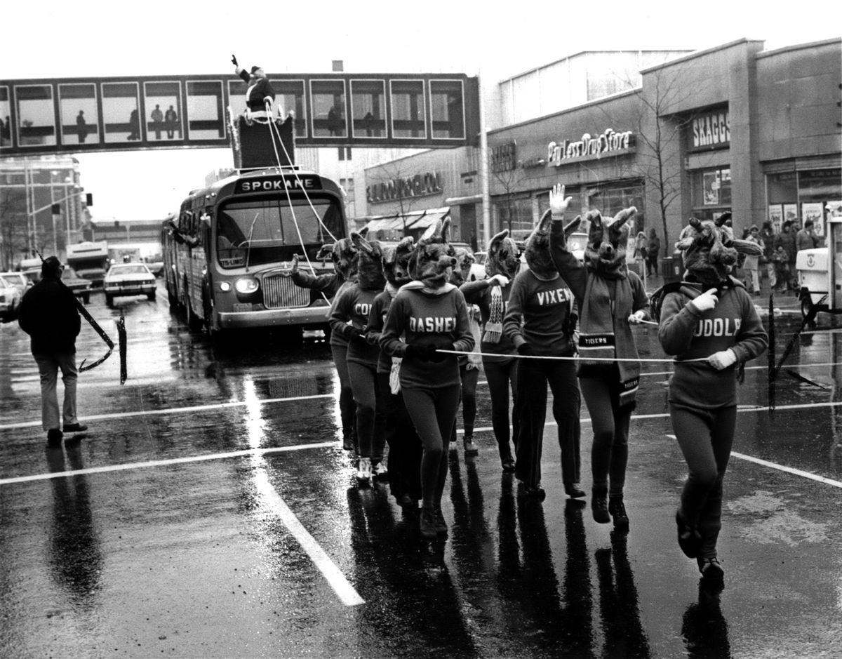 1977: Santa Claus arrived in rainy downtown Spokane riding in a sleigh mounted on a special Spokane Transit System bus in a parade down Main Avenue on the way to Riverfront Park. The “reindeer” were Lewis and Clark High School students wearing masks made in a home economics class. LCHS woodworking students built the sleigh. Percussion Naut Patriots marching band also joined the parade. The Chamber of Commerce’ Retail Trade Bureau organized the holiday shopping kickoff, as they had for many decades, starting in the 1920s. (Spokesman-Review Photo Archives)