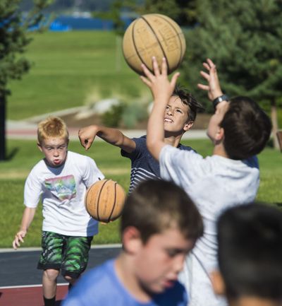 Thomas Taylor, center, and Justin Fagan, left, execute dribbling and shooting drills for coach James Anderson during a Tuesday morning practice, July 11, 2017, at McEuen Park in Coeur d’Alene, Idaho. The boys are preparing to play AAU basketball next season. (Dan Pelle / The Spokesman-Review)