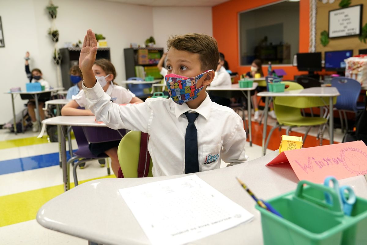 FILE - In this Monday, Aug. 23, 2021, file photo, student Winston Wallace, 9, raises his hand in class at iPrep Academy on the first day of school in Miami. A judge has ruled that Florida school districts may impose mask mandates. Leon County Circuit Judge John C. Cooper on Friday agreed with a group of parents who claimed in a lawsuit that Gov. Ron DeSantis