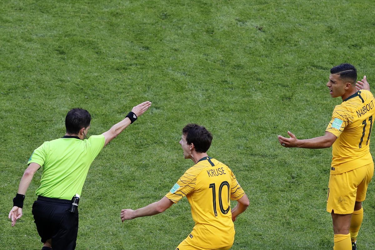 Australia’s Robbie Kruse, center, and Andrew Nabbout, right, react after referee Andres Cunha from Uruguay, left, awards a penalty after watching a replay on a screen during the Group C match between France and Australia at the 2018 soccer World Cup in the Kazan Arena in Kazan, Russia, Saturday, June 16, 2018. (Hassan Ammar / Associated Press)