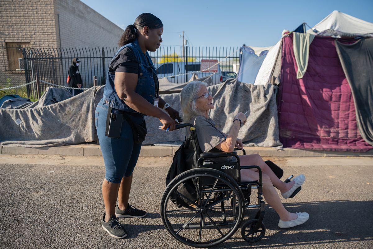 Nette Reed checks on Desi Hurd, 62, near the Human Services Campus in Phoenix, where there are several major shelters, a medical center and respite centers.  (Caitlin O