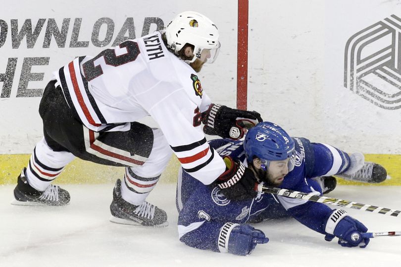 Tampa Bay’s Tyler Johnson, right, hits the ice as he fights for control of the puck against Duncan Keith. (Associated Press)