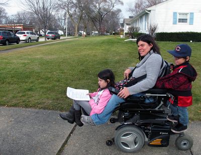 In this Nov. 19, 2012 photo, twins Abigail and Noah Thomas, 8, ride on the motorized wheelchair of their mother, Jenn Thomas, on their way to a school book fair in Arlington Heights, Ill. Thomas, a 36-year-old mom who has cerebral palsy, says her twins occasionally complain about having to do a few extra chores around the house to help her. Abigail nods and smiles upon hearing this, but says for the most part, their lives are 